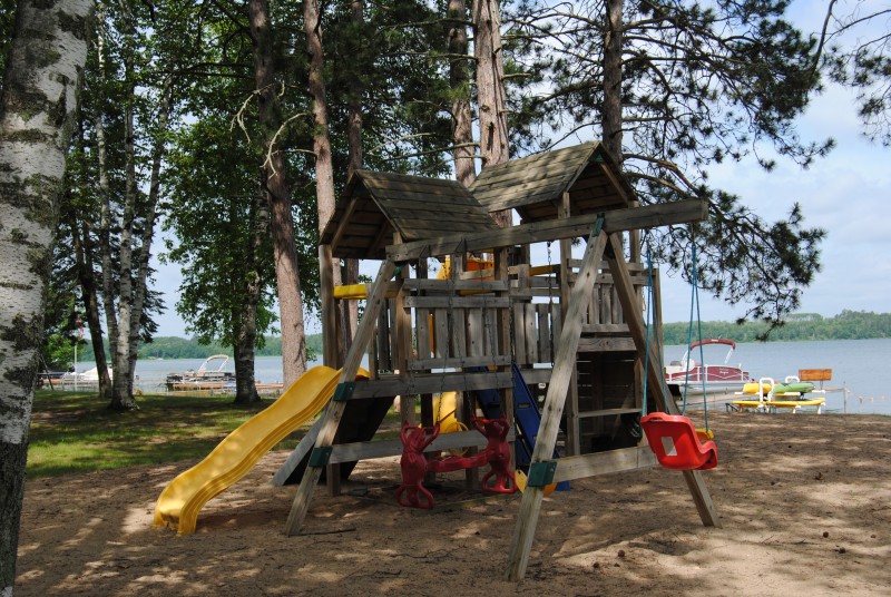 Wooden playground with climbing wall, slides, and swing set